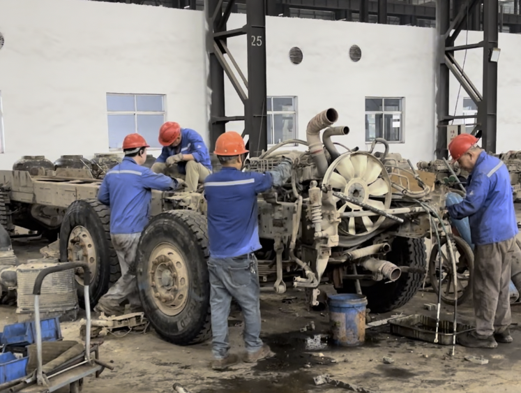 Teknikistoj laborantaj ĉirkaŭ senŝirma peza kamiona ĉasio